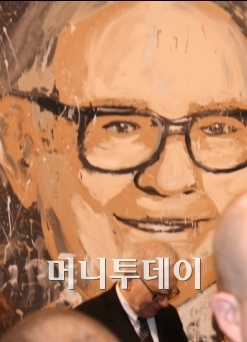 ↑ 자신의 대형 초상화 앞에서 주주들에게 사인해주고 있는 워런 버핏 ⓒ오마하=김준형 특파원