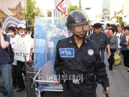↑시위 진압경찰 복장을 한 시민이 '닭장차'를 끌고 있다