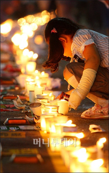 ↑ 10일 저녁 서울 광화문네거리에서 열린 미국산쇠고기 수입반대 촛불시위에 참석한 한 어린이가 광화문에서 서대문 방향으로 이어진 촛불 띠를 연결하고 있다. ⓒ이명근 기자