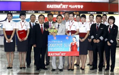 ↑이스타항공은 26일 김포공항에서 200만번째 탑승객인 정세준씨(37·사진 왼쪽 4번째) 씨에게 국제선 왕복 항공권 2매를 전달했다.