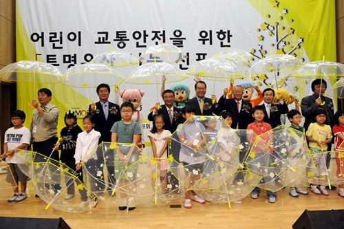 ↑지난 9일 서울 영등포 우신초등학교에서 열린 ‘투명우산 나눔’ 행사에서 참석자들이 어린이들에게 투명 우산을 나눠주고 있다. <br>
