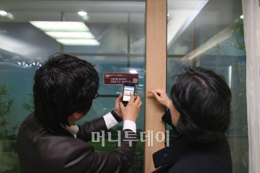 ↑ 모델하우스 방문자가 스마트폰으로 모델하우스에 사용된 창호에 대한 정보를 확인하고 있다. 