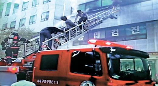 22일 오후 불이 난 서울 강남구 삼성동 5층짜리 건물의 사무실에서 직원들이 연기를 피해 소방차의 고가사다리를 타고 탈출하고 있다. [강남 소방서 제공]<br>
