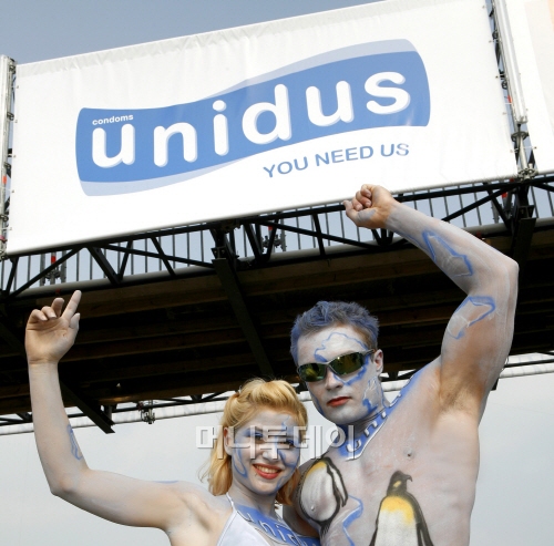 세계 최대의 테크노파티 독일 '러브 퍼레이드'에 설치된 유니더스 광고판 앞에서 참가자들이 포즈를 취하고 있다. 유니더스는 글로벌 콘돔시장의 약 30%를 점유하고 있다. (사진제공=유니더스)
