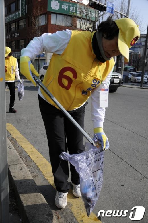 양형일 후보 선거사무원이 동구 거리에서 쓰레기를 줍고 있다.  News1