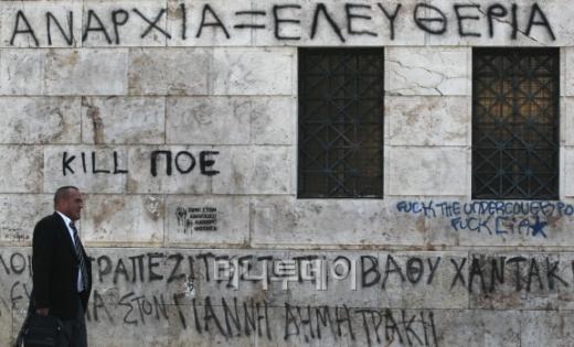 ↑ 아테네대학 담벼락에 가득한 낙서들 사이로 한 시민이 지나가고 있다. 그리스에선 청년실업률이 50%를 넘어서면서 청년들의 정치와 기성세대에 대한 불만도 커지고 있다. ⓒ아테네(그리스)=홍봉진 기자