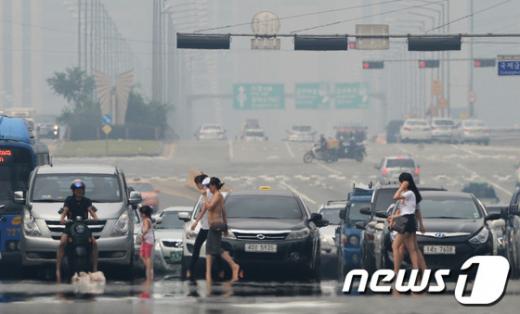 폭염이 이어지고 있는 9일 오후 서울 여의대로에 피어오른 아지랑이 사이로 시민들이 지나고 있다. 2013.8.9/뉴스1  News1   양동욱 기자