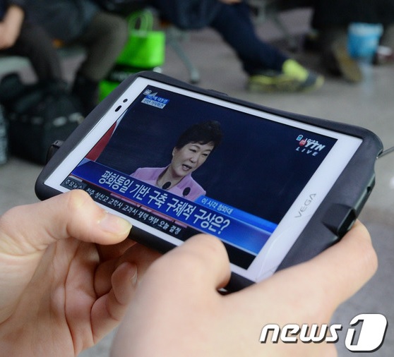 한 시민이 6일 박근혜 대통령 기자회견을 스마트폰으로 시청하고 있다. 대통령이 강력한 의지를 갖지 않으면 개헌 추진은 사실상 어렵다는 게 정치권 공감대다./뉴스1<br>
