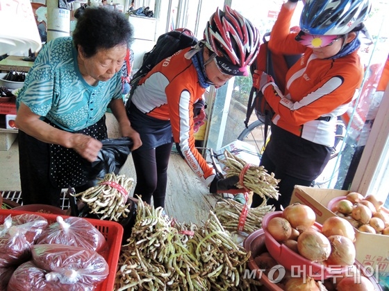 레포츠열차 참가자들이 19일 서천특화시장에서 지역 농산물을 구입하고 있다./사진=이고운 기자<br>
