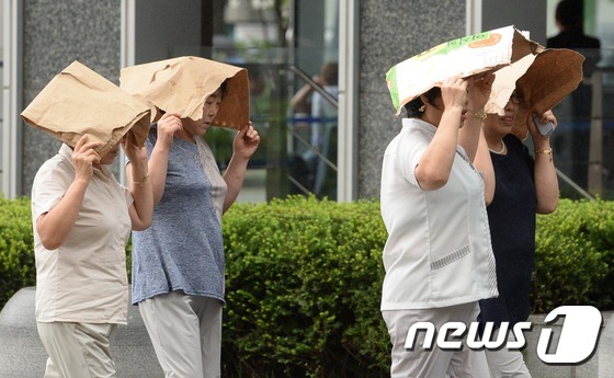 서울 지역에 산발적으로 비가 내린 19일 오후 서울 광화문 일대에서 우산을 준비하지 못한 시민들이 종이를 이용해 비를 피하고 있다. / 사진=뉴스1