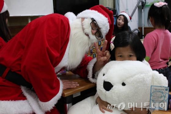 부스러기사랑나눔회와 LG디스플레이가 연 '크리스마스의 기적' 중 모 지역아동센터의 아동이 그동안 받고 싶어하던 곰인형을  '산타'로부터 선물 받고 있다./사진=부스러기사랑나눔회