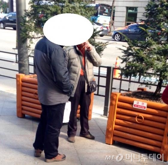금연 표지판 앞에서 담배를 피우는 중국 관광객들. 