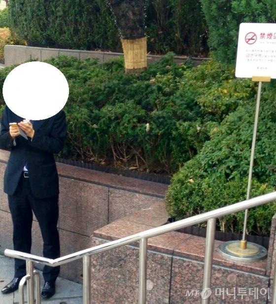 금연 표지판 앞에서 담배를 피우는 중국인.