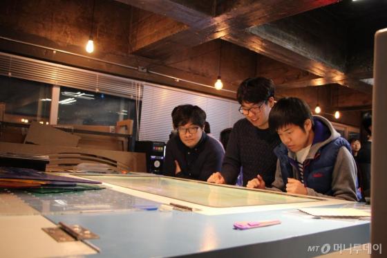 팹랩 서울에서 레이저 커터를 이용해 아이디어를 상품으로 직접 만들어보고 있는 청년들