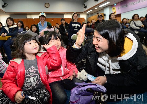 지난 10일 오후 서울 시내 한 유치원에서 열린 2015학년도 신입생 추첨식에 당첨된 학부모가 자녀와 함께 기뻐하고 있다. /뉴스1
