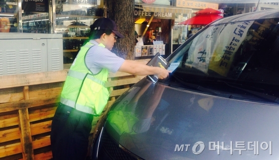 서울시 불법주차 단속원들이 불법주차 된 차량에 단속고지서를 끼워넣고 있다. /사진=남형도 기자