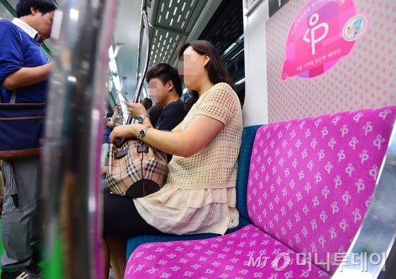  23일 오후 서울 지하철 2호선에 임산부 배려석임을 쉽게 알아볼 수 있도록 분홍색으로 꾸민 열차가 시범운행되고 있다.  서울시는 현재 열차 양 끝에 위치한 교통약자 지정석 외에 열차 한 칸 당 두 좌석을 임산부 배려석으로 별도 운영하고 있다. 그러나 시는 승객이 자리에 앉으면 벽에 붙어 있는 엠블럼이 가려져 임산부 배려석이라는 사실을 알아채기 쉽지 않은 점을 개선하기 위해 새 디자인을 개발했다고 밝혔다. 2015.7.23/뉴스1  <저작권자 © 뉴스1코리아, 무단전재 및 재배포 금지>