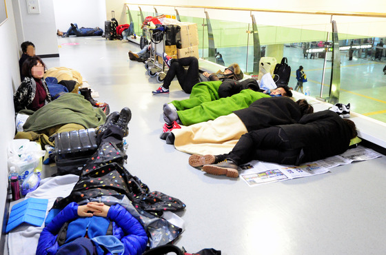 제주공항이 폭설로 전편 결항된 가운데 24일 공항 대합실에 승객들이 종이상자를 펴고 잠을 자고 있다. / 사진제공=뉴스1