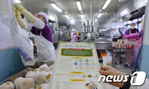 서울 강북구 한 초등학교 급식실에서 영양사가 식중독 예방요령 안내문을 들고 있다./뉴스1 © News1 박지혜 기자
