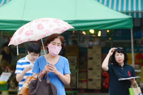 서울 서남권역에 오존주의보가 발령된 24일 오후 서울 양천구 일대에서 한 시민이 양산을 쓰고 지나가고 있다./사진=뉴스1