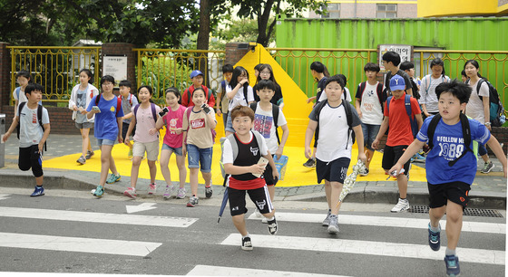  녹색어머니회 교사들과 구청 공무원들이 7일 서울 광진구 구남초등학교 앞 통학로에서 아이들의 안전한 등하굣길을 위한 '옐로카펫'을 깔고 있다. '옐로카펫'은 횡단보도 앞 바닥과 대기공간 벽면에 노란색 표시를 해 보행자는 옐로카펫에서 대기하고, 운전자는 보행자를 확인할 수 있도록하는 교통사고 예방시설이다./사진=뉴스1