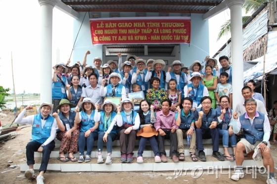 지난 26일 베트남 해외자원봉사에 참가한 아주봉사단원들이 메콩강 인근 빈곤가정의 '사랑의 집짓기' 현장에서 마을 주민들과 기념촬영을 하고 있다/사진제공=아주그룹<br> 