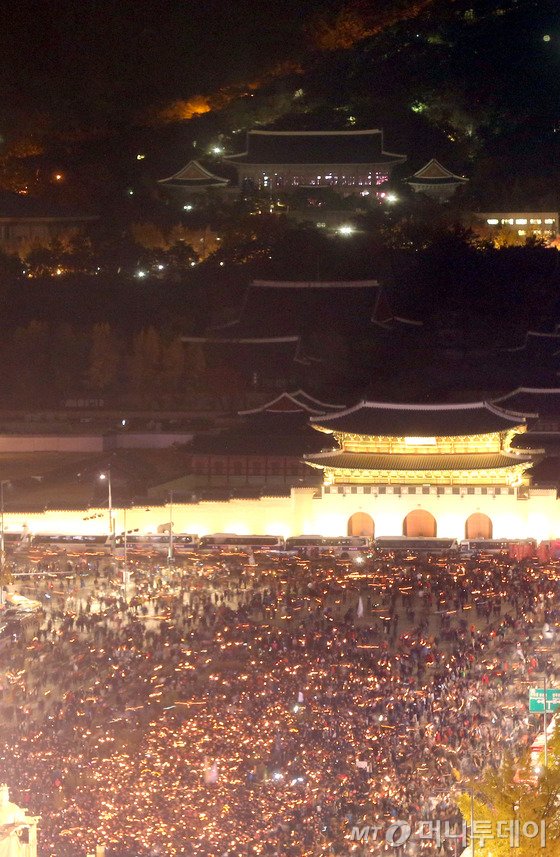  박근혜 대통령 퇴진을 요구하는 민중총궐기 대회가 열린 12일 밤 촛불을 든 광화문 광장의 시민들 뒤로 불켜진 청와대가 보인다.(사진공동취재단)2016.11.12/뉴스1 