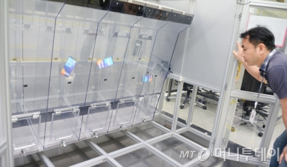 LG전자 연구원이 약 1미터 높이의 투명한 사각 통에 LG G6를 넣고 끊임없이 회전시키는 '연속 낙하 시험'을 실시하고 있다./사진제공= LG전자