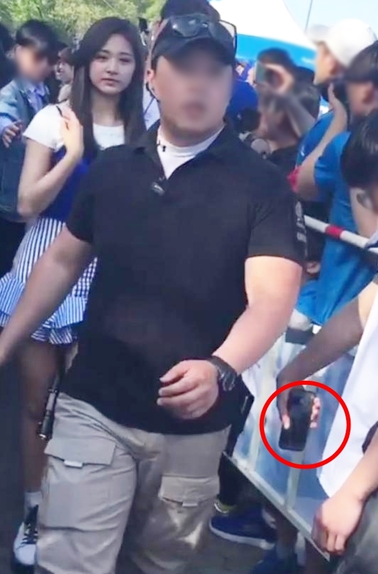 트와이스 팬이 트위터에 올린 사진. 한 남성이 휴대폰을 들고 멈춰 서 지나가는 트와이스 멤버의 다리를 찍는 모습이 포착됐다./사진=트위터 캡처