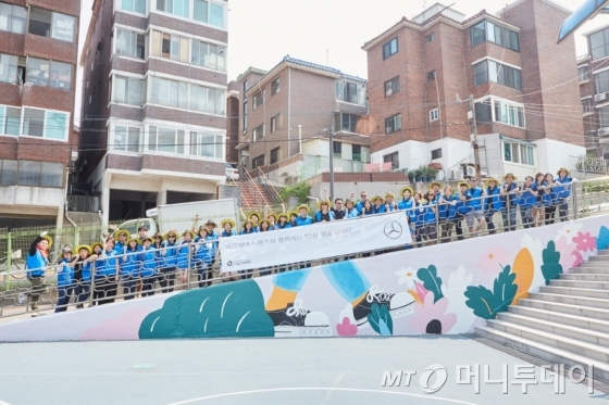 메르세데스-벤츠 사회공헌위원회가 지난 17일 서울 은평구 상신초등학교에서 '안심 학교 담벼락 그리기' 봉사활동을 진행했다. 참여한 임직원들이 사진을 찍고 있다./사진=메르세데스-벤츠 코리아