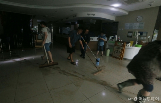 23일 인천 남구 한 병원에서 도로에 침수된 빗물이 내부로 들어오면서 정전되자 관계자들이 분주하게 빗물을 쓸어내며 복구에 힘쓰고 있다. /인천=이기범 기자 