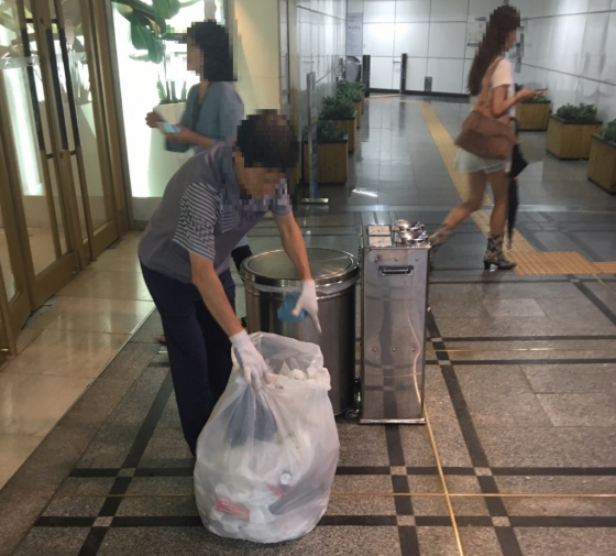 31일 오후 서울 중구 소공동 롯데백화점 본점 입구에서 한 직원이 우산 비닐커버 등이 담긴 쓰레기 봉지를 정리하고 있다./사진=남형도 기자