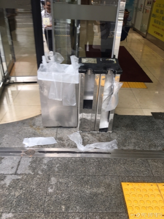 광화문 일대 한 건물에 설치된 우산 비닐커버 포장기. 인근에는 사람들이 버리고 간 우산 비닐커버가 나뒹굴고 있다./사진=남형도 기자