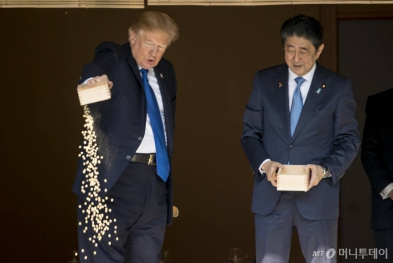 도널드 트럼프 미국 대통령이 6일 도쿄 아카사카궁에서 나무 통에 담긴 먹이를 숟가락으로 퍼서 연못의 비단잉어들에게 주다가 한꺼번에 쏟아붓고 있다. /사진=뉴시스