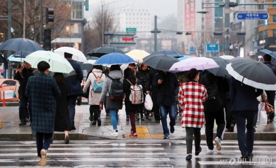 겨울비가 내리는 서울 광화문 사거리에 우산을 쓴 시민들이 걸음을 재촉하고 있다.