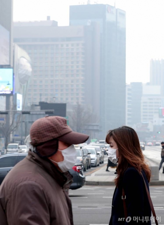 서울시가 서울형 미세먼지 비상저감조치를 발령한 17일 오전 서울 광화문 사거리 인근에서 시민들이 마스크를 쓰고 발걸음을 재촉하고 있다.