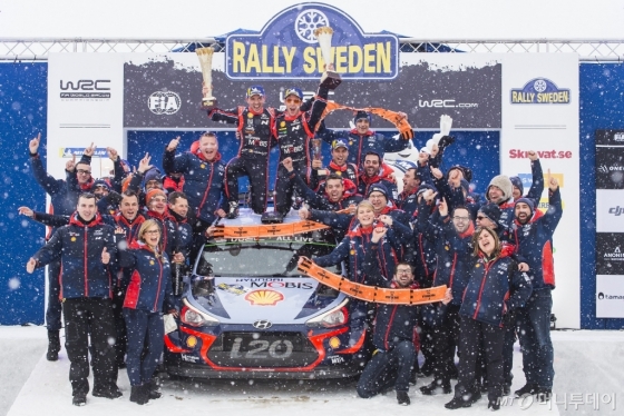 2018 WRC 스웨덴 랠리에서 우승을 차지한 현대 월드랠리팀 선수와 관계자들이 시상대에서 기념 사진을 찍고 있다. 팀 소속 니콜라스 질술(왼쪽)과 티에리 누빌(오른쪽)이 신형 i20 랠리카 위에서 우승컵을 들고 환호하고 있다./사진제공=현대차 