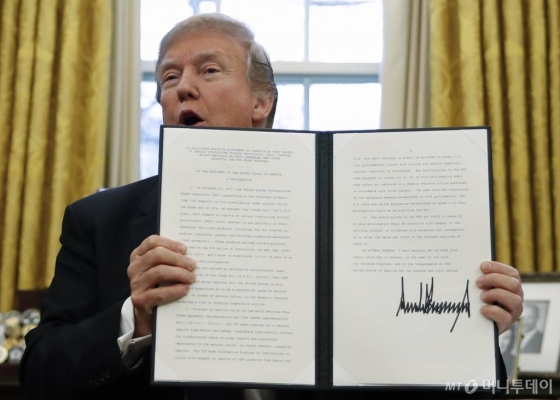 도널드 트럼프 미국 대통령은 23일(현지시간) 백악관에서 수입 세탁기와 태양광 제품에 대한 세이프가드(긴급수입제한) 조치에 서명한 후 문서를 들어보이고 있다. /AP 뉴시스