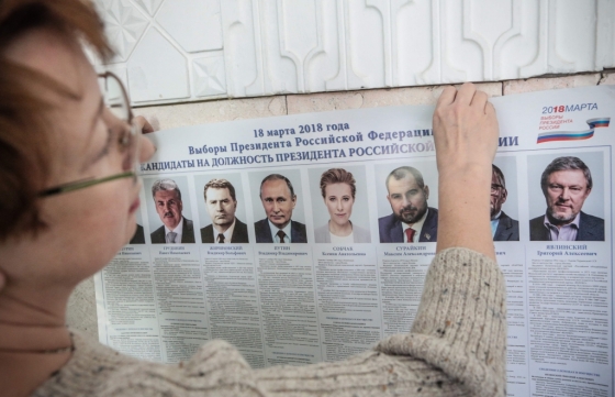 17일(현지시간) 러시아 크림반도의 한 대선 투표소에서 한 여성이 블라디미르 푸틴 현 러시아 대통령이 포함된 선거 포스터를 붙이고 있다. /AFPBBNews=뉴스1