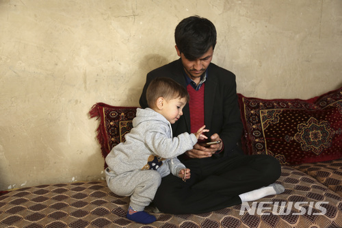 아사둘라 포야가 아프가니스탄 카불에 있는 자신의 집에서 3째 아들 도널드 트럼프와 함께 휴대폰으로 트럼프 미국 대통령의 사진을 보고 있다. /사진제공= 뉴시스