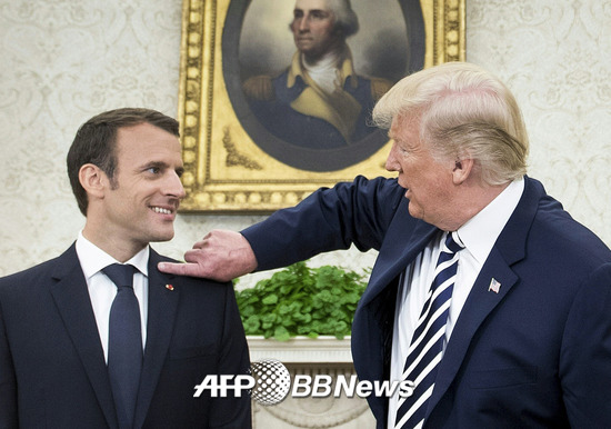 에마뉘엘 마크롱 프랑스 대통령의 어깨에 묻은 비듬을 털어주고 있는 도널드 트럼프 미국 대통령. /AFPBBNews=뉴스1