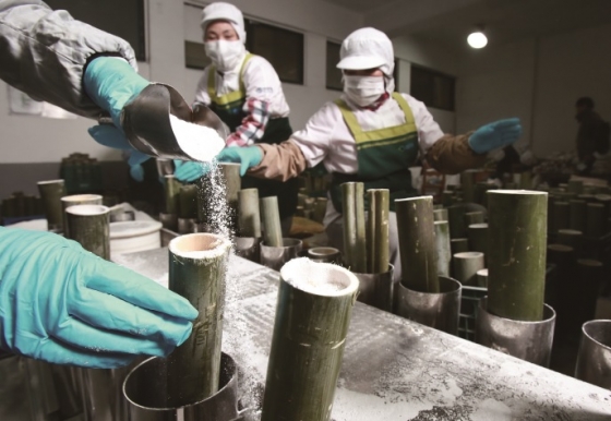 죽염 전문기업 인산가의 근로자들이 가열 전 죽염을 대나무통에 넣고 있는 모습. / 사진제공=인산가