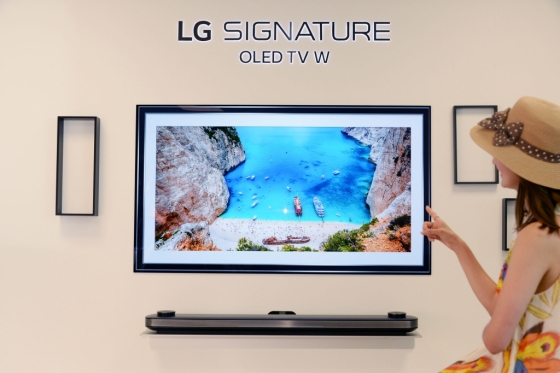LG전자 모델들이 'LG 시그니처 올레드 TV W'의 갤러리 앱에서  트립어드바이저가 추천하는 여름 여행지 사진을 보고 있다. /사진제공=LG전자