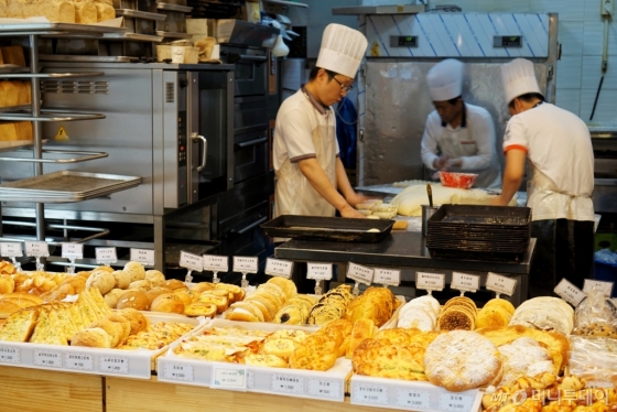 지난 11일 서울 동대문구 이문동 '빵이가'에 소보로, 찹쌀도넛 등 다양한 빵이 진열돼있고 그 뒤로 바쁘게 움직이는 제빵사들이 보인다. /사진=남궁민 기자