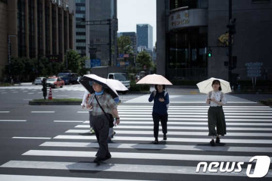 지난달 23일, 일본 도쿄에서 시민들이 더위를 피해 양산을 쓴 채 걸어가고 있다. /AFP=뉴스1