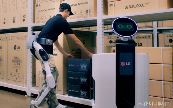  'LG 클로이 수트봇'을 착용한 작업자가 물류센터에서 상품을 쇼핑카트로봇에 옮겨담고 있는 모습/사진제공=LG전자