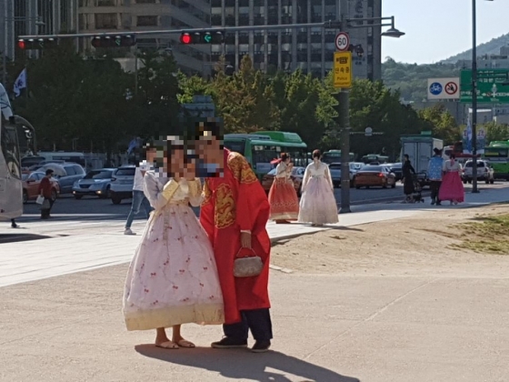 경복궁을 찾은 외국인 관광객 커플이 퓨전한복과 용포를 입고 사진을 찍고 있다.