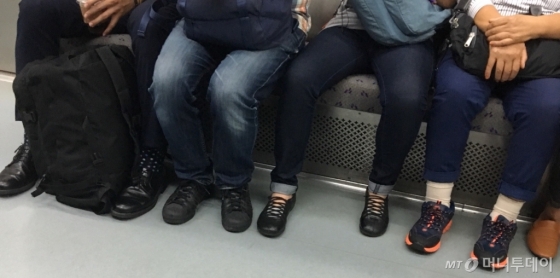 지난 21일 서울 지하철 5호선에서 다리를 쫙 벌리고 앉은 승객. 반면 옆 좌석 승객은 다리를 오므리고 있다./사진=남형도 기자
