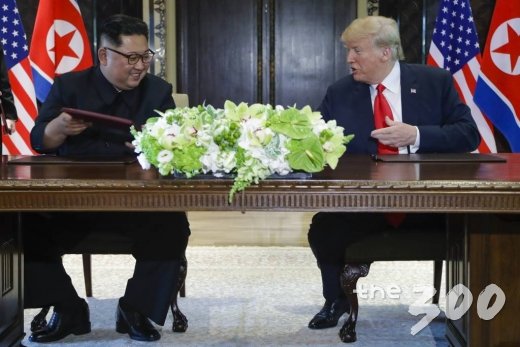 【싱가포르=AP/뉴시스】도널드 트럼프 미국 대통령과 김정은 북한 국무위원장이 12일 싱가포르 센토사 섬 내 카펠라 호텔에서 합의문에 서명한 후 웃고 있다