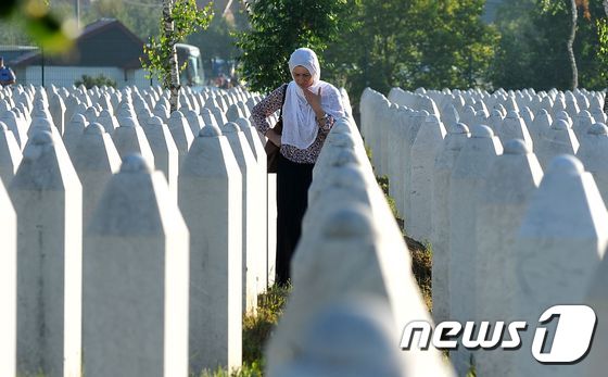 2016년 7월11일 보스니아 헤르체고비나 스레브레니차 포토차리의 추모묘지에서 1995년 스레브레니차 집단 학살 당시 생존한 무슬림 여인이 친지의 묘 곁에서 애도를 하고 있다./AFPBBNews=뉴스1